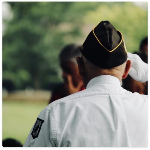 Man from back in military suit saluting other people