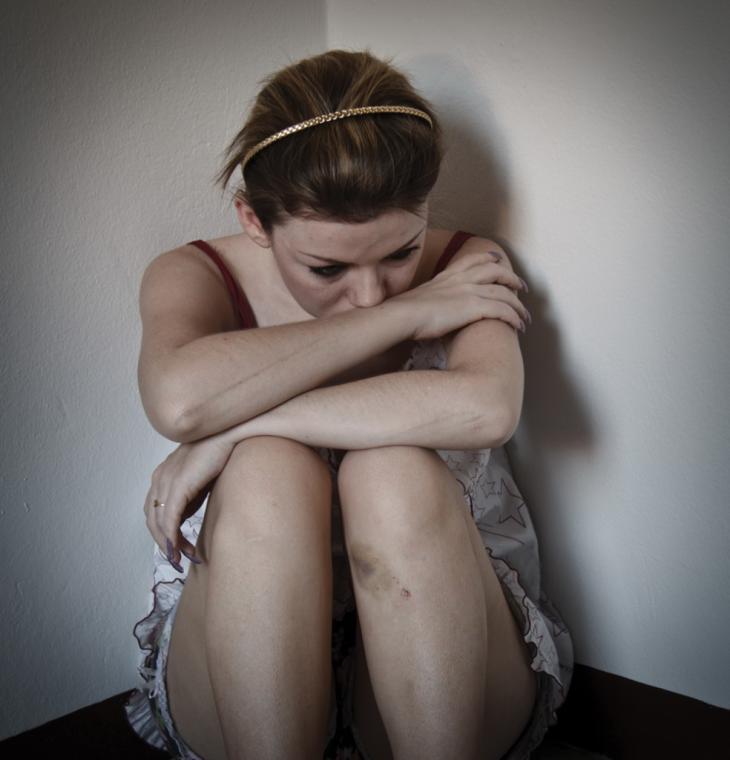 woman sitting hiding against wall